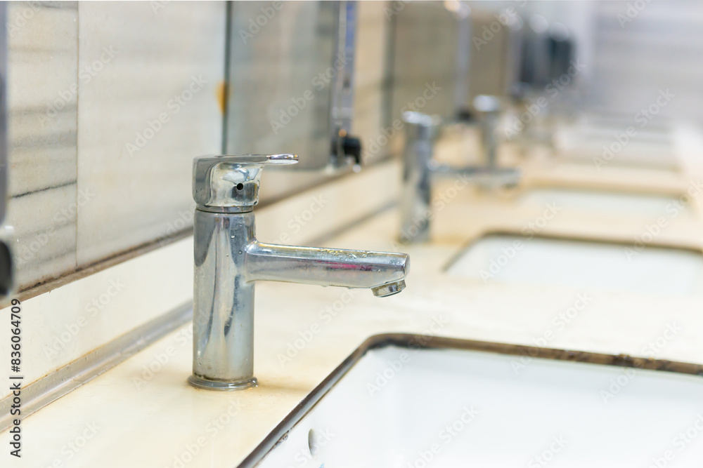 Public bathroom restroom lavatory interior with row of white ceramic sinks, mirrors and faucets Public bathroom restroom lavatory interior with row of white ceramic sinks, mirrors and faucets