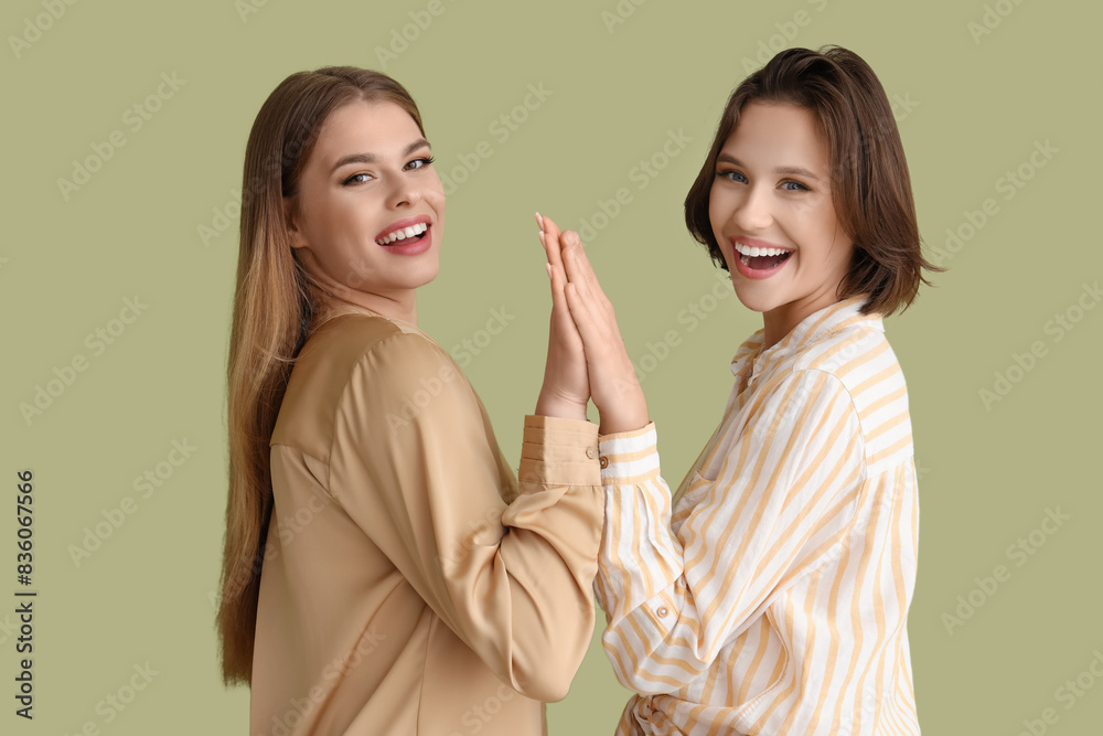 Female friends holding hands on green background Female friends holding hands on green background
