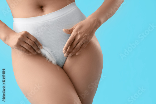 Young woman in panties with feather on blue background