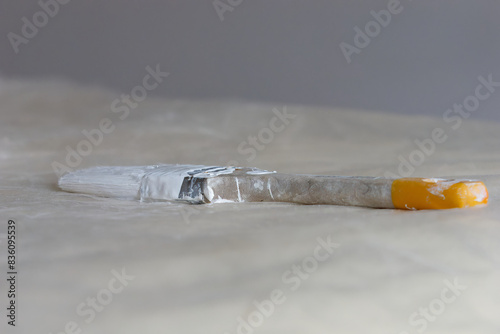 Obraz na płótnie Selective focus photo of a wall brush stained with white paint on a bed covered