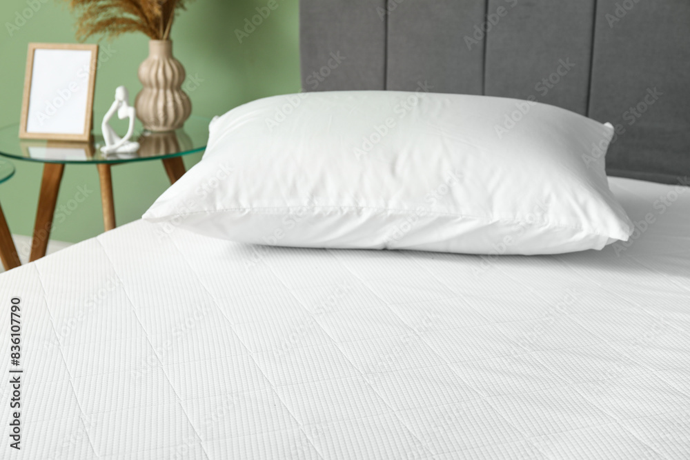 Obraz premium New orthopedic mattress on stylish bed near green wall in room, closeup