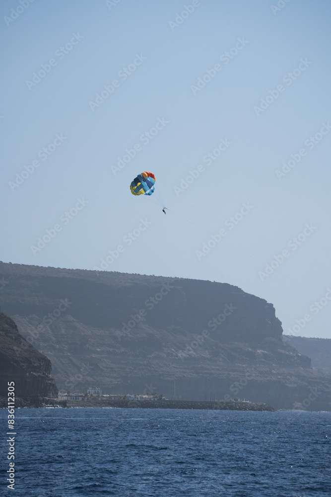 Parasailing against cliff in Tauro beach (Spanish: Playa de Tauro) near the Puerto Rico de Gran Canaria holiday resort on Gran Canaria island, Spain
