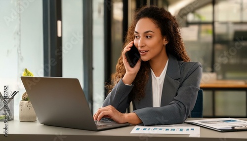 A mature, busy and happy businesswoman, an older female executive, is standing in her office and using a digital tablet. The middle-aged professional businesswoman is a bank manager and uses a tablet 