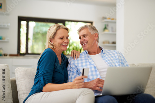 Mature, couple and laptop with credit card on couch for online shopping, payment and saving plan. People, home and happy on sofa in living room for internet banking, budget and investment or finance © peopleimages.com