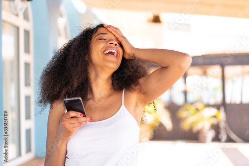 Young African American woman using mobile phone at outdoors has realized something and intending the solution