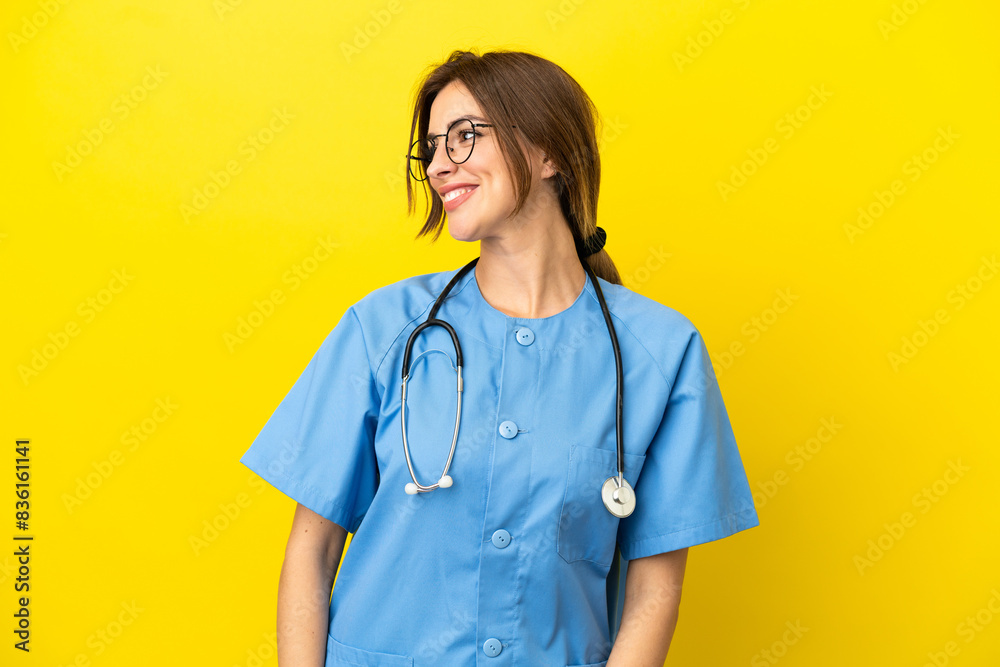 Surgeon doctor woman isolated on yellow background looking side Surgeon doctor woman isolated on yellow background looking side