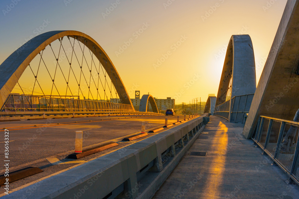 Obraz premium Sunset Skyline Over Modern Arched Bridge