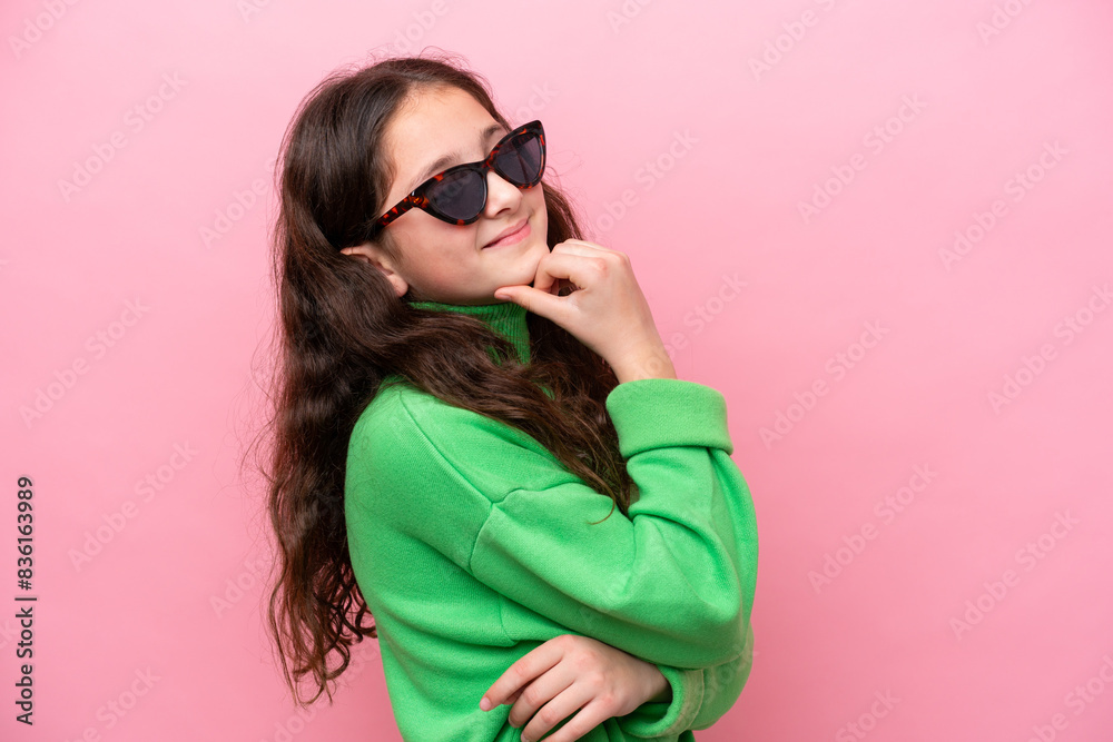 Little caucasian girl wearing sunglasses isolated on pink background looking side Little caucasian girl wearing sunglasses isolated on pink background looking side