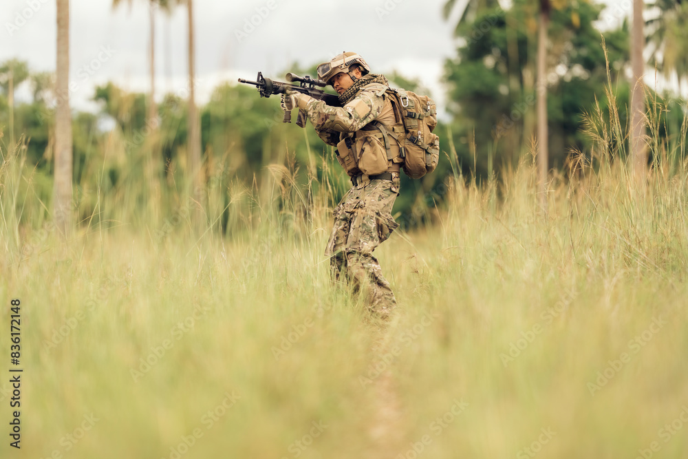 Within the hazardous jungle battlefield, soldiers holding M16 rifles patrol amidst the surrounding grasslands, poised to repel enemy assaults from all directions to maintain territorial security.