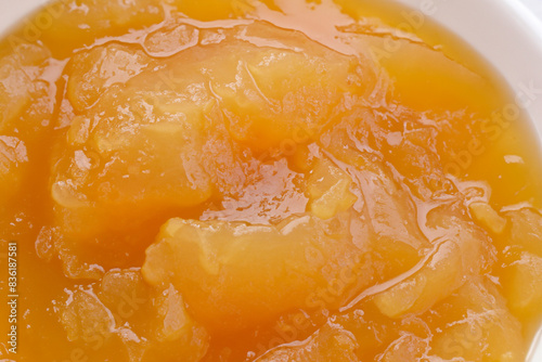 fruit puree. a large amount of orange applesauce lies in a white plate, top view close up concept useful
