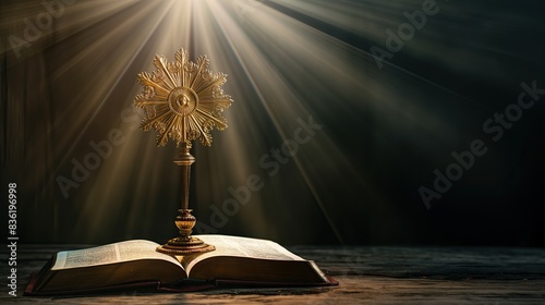 monstrance and open Holy Bible with sun rays of light from above, on black background for overlay photo