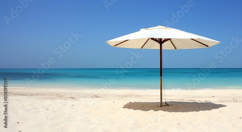 A white umbrella is on a beach with a blue ocean in the background. The scene is peaceful and relaxing