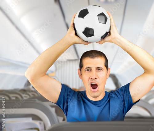 Fan sport player on blue uniform celebrating with football or soccer ball at airplane © cunaplus