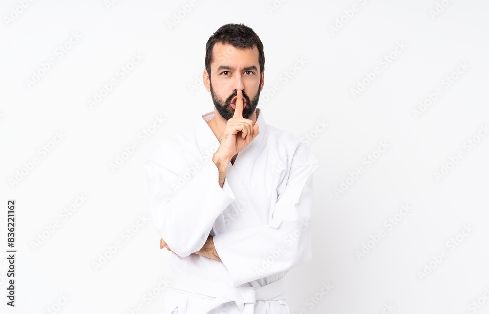 Young man doing karate over isolated white background showing a sign of silence gesture putting finger in mouth Young man doing karate over isolated white background showing a sign of silence gesture putting finger in mouth