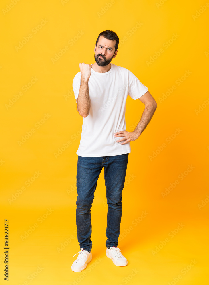 Full-length shot of man with beard over isolated yellow background with angry gesture Full-length shot of man with beard over isolated yellow background with angry gesture