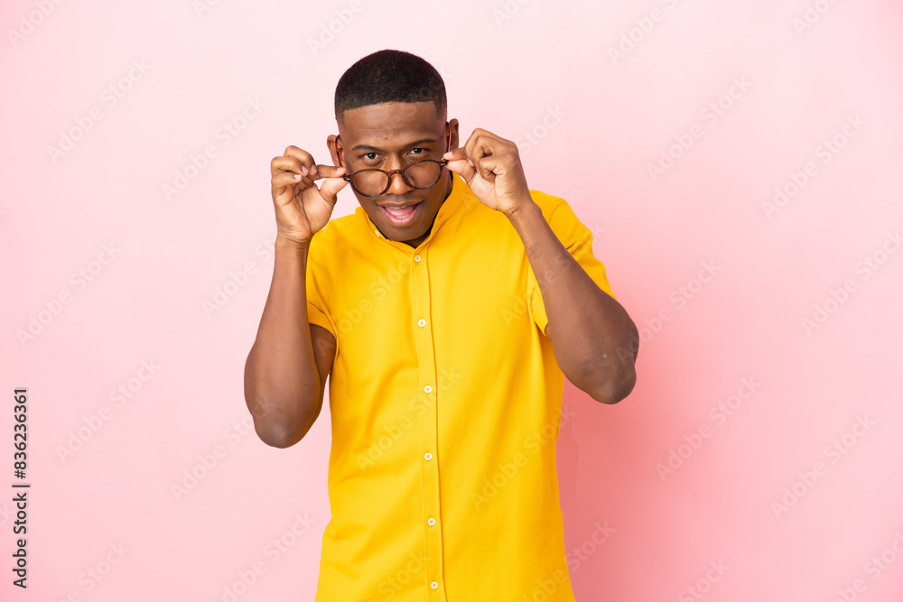 Young latin man isolated on pink background with glasses and surprised Young latin man isolated on pink background with glasses and surprised