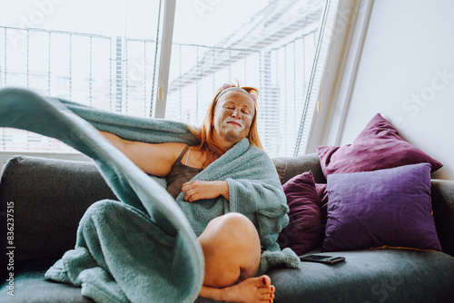 portrait middle-aged woman with cosmetic mask on face on sofa at home