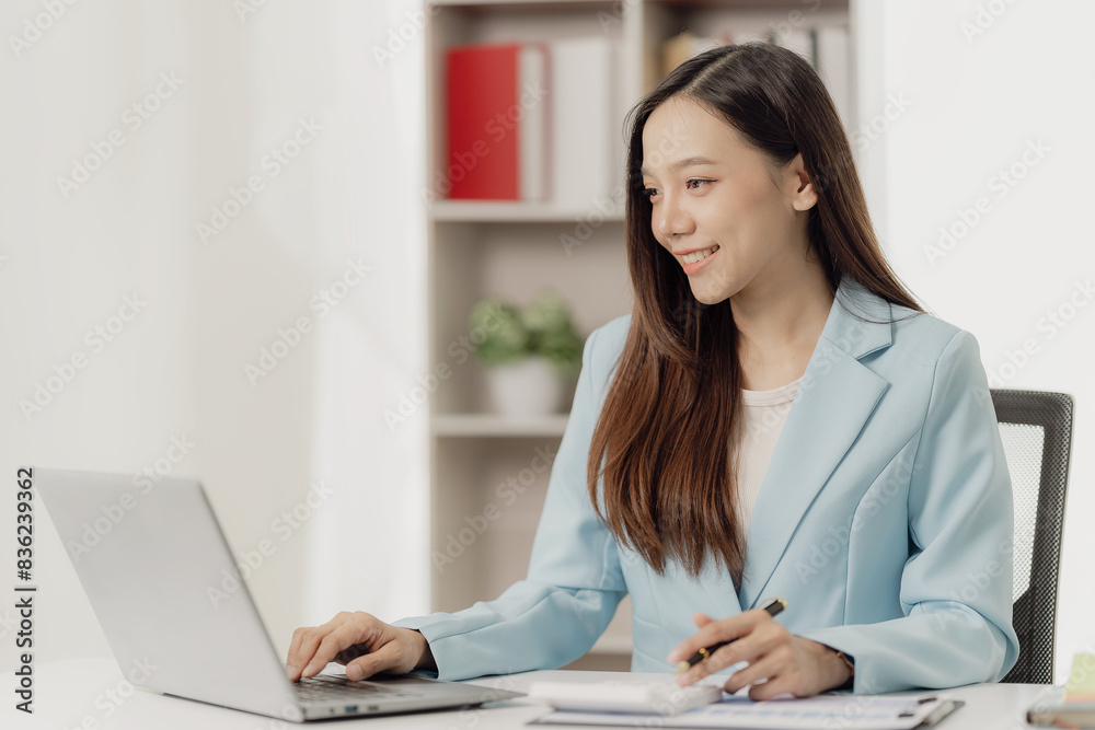 Businesswoman working on financial documents on the desk in the office is writing notes and calculating income and expenses. Businesswoman working on financial documents on the desk in the office is writing notes and calculating income and expenses.