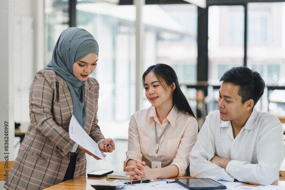 Businesswoman presenting information on tablet to colleagues in office meeting. Businesswoman presenting information on tablet to colleagues in office meeting.