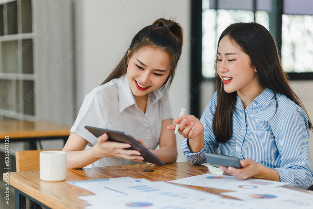 Two businesswomen reviewing data on a tablet in an office. Two businesswomen reviewing data on a tablet in an office.