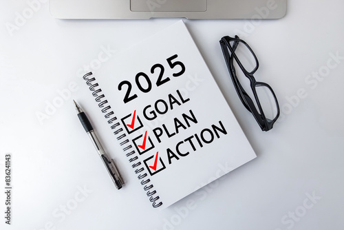 2025 Goal, Plan, Action checklist text on note pad with laptop, glasses and pen.