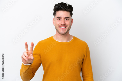 Young caucasian man isolated on white background smiling and showing victory sign
