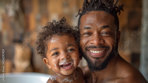 Delightful father and young child laughing together while covered in soap suds during bath photo
