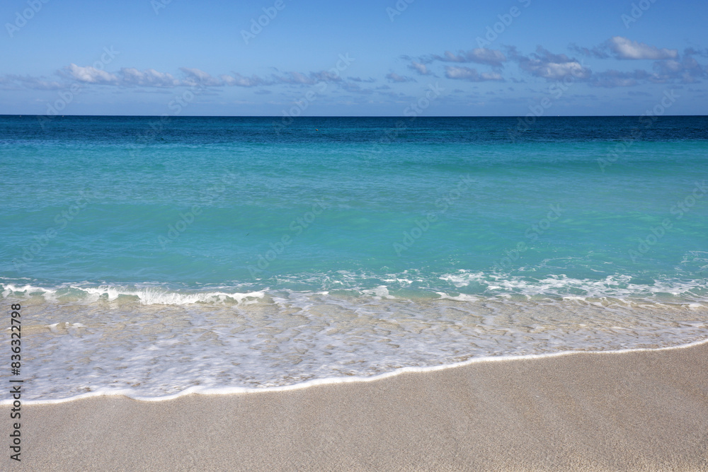 Empty sea beach with white sand, view to azure waves and blue sky with cloud. Caribbean coast, background for holidays on a paradise nature