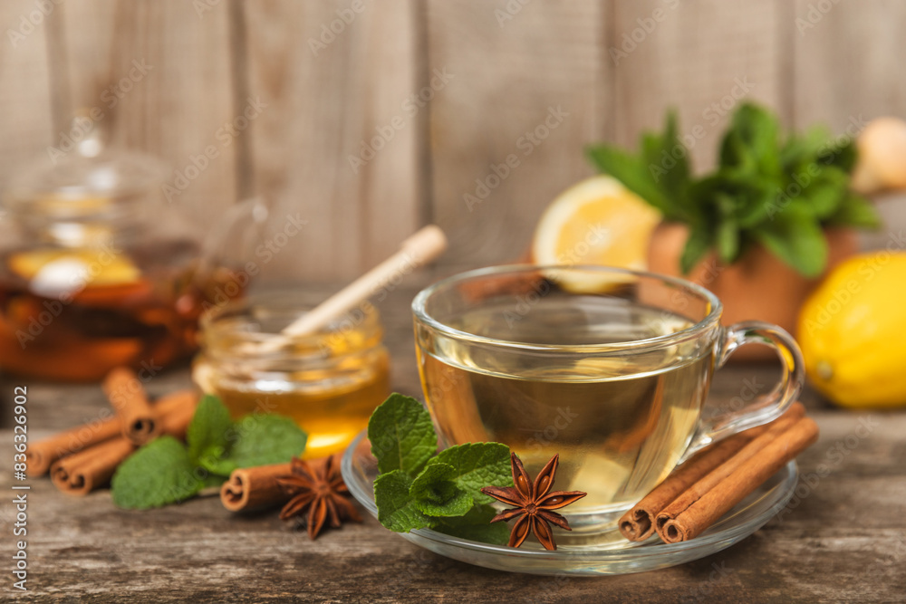 Fragrant hot tea with cinnamon stick and anise on a textured wooden background. A cup of hot tea with honey, lemon, mint and apples. Spicy tea with spices. Immunity tea. Health concept.Copy space. Fragrant hot tea with cinnamon stick and anise on a textured wooden background. A cup of hot tea with honey, lemon, mint and apples. Spicy tea with spices. Immunity tea. Health concept.Copy space.