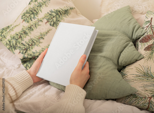 Blank book mockup with cover. Hand holding white paper template. Woman s background design for empty female business. Cozy warm bed with pillow view. Hold closed diary page photo