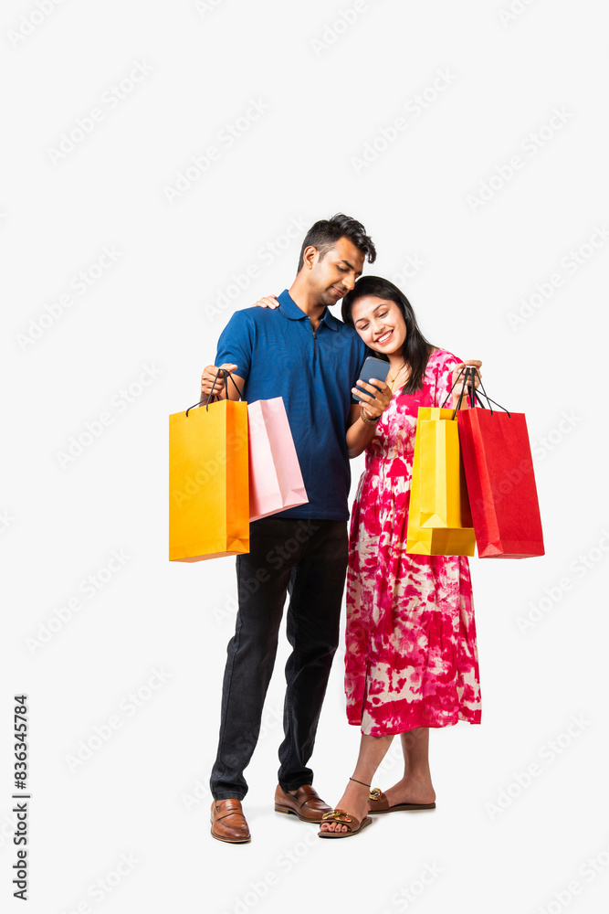 Asian Indian smart and young couple showing shopping bags standi Asian Indian smart and young couple showing shopping bags standi