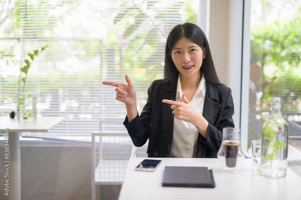 Professional businesswoman working pointing finger in a bright, modern cafe with coffee and greenery Professional businesswoman working pointing finger in a bright, modern cafe with coffee and greenery