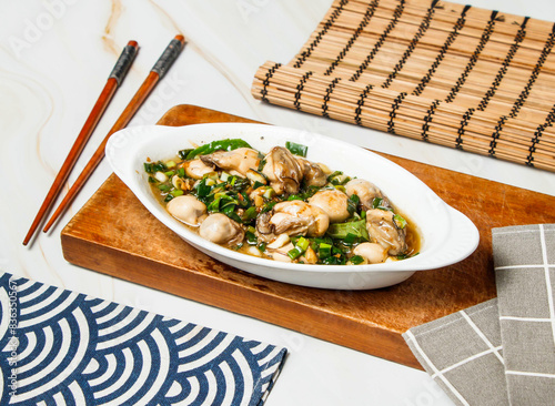 Stir aFried Oysters with chopsticks served in dish isolated on wooden board and napkin side view of taiwan food photo