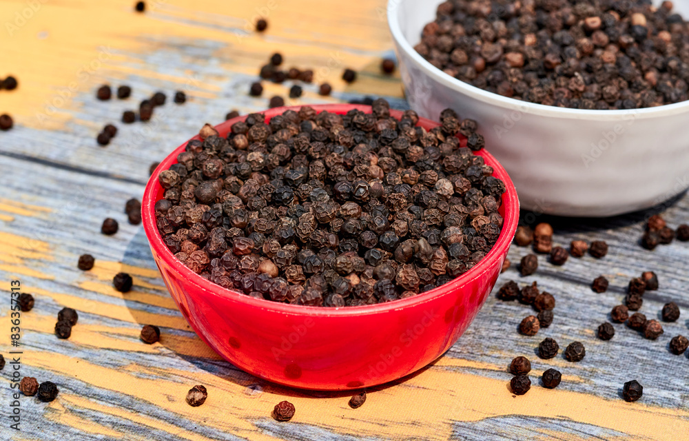 bowls filled with black peppers (Piper nigrum). Native to Malabar coast of India, it is widely used in culinary as spice and seasoning around the world. bowls filled with black peppers (Piper nigrum). Native to Malabar coast of India, it is widely used in culinary as spice and seasoning around the world.