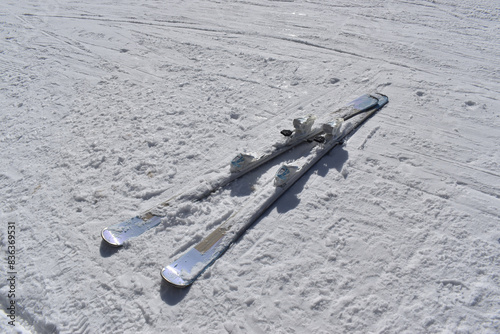 Winter time and ski-run on a mountain with two skis covered with snow
