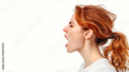 Close up profile of a young, red hair, Caucasian woman with mouth open wide, shouting. Isolated on white, copy space, aspect ratio 16:9 photo