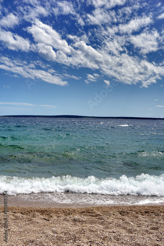 Turquoise sea water near the pebble beach bellow stunning sky