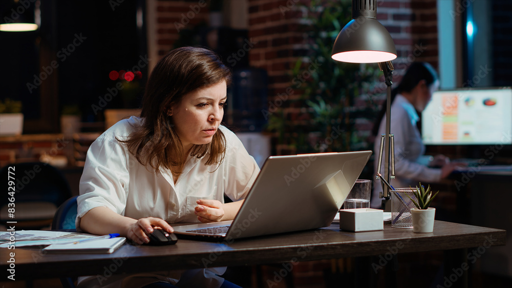 Employee calling manager to her computer desk to ask for feedback on project progress. Worker in office late at night requesting assistance from team leader on tasks done on laptop Employee calling manager to her computer desk to ask for feedback on project progress. Worker in office late at night requesting assistance from team leader on tasks done on laptop
