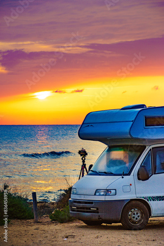 Camper and camera on tripod on beach at sunrise