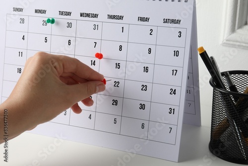Timetable. Man marking date in calendar with drawing pins at white table  closeup
