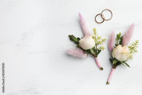 Quadro su tela Small stylish boutonnieres and rings on white marble table, flat lay