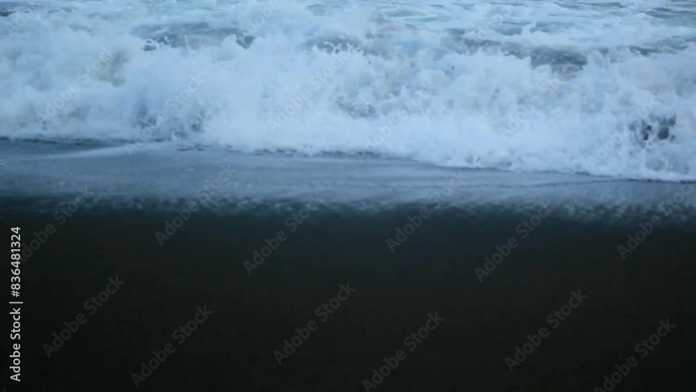 As the tide sweeps in at South Jogja Beach, under a serene sky, waves gently roll, accompanied by ripples and bubbling foam. As the tide sweeps in at South Jogja Beach, under a serene sky, waves gently roll, accompanied by ripples and bubbling foam.