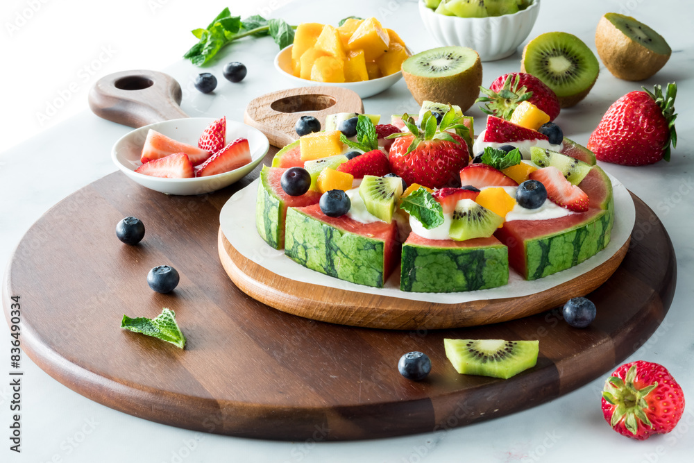 A homemade watermelon pizza topped with pieces of fresh fruit A homemade watermelon pizza topped with pieces of fresh fruit