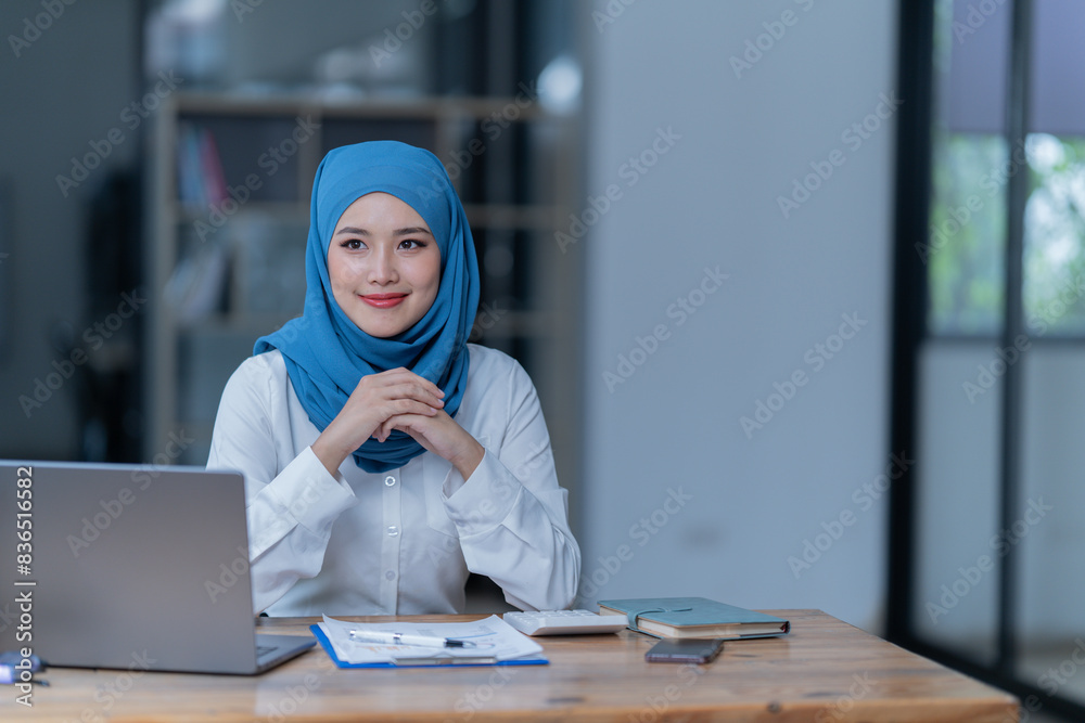 Cheerful muslim lady wear hijab working in the office, using laptop, Side view of smiling arab woman, freelancer typing on laptop, Muslim working woman concept. Cheerful muslim lady wear hijab working in the office, using laptop, Side view of smiling arab woman, freelancer typing on laptop, Muslim working woman concept.