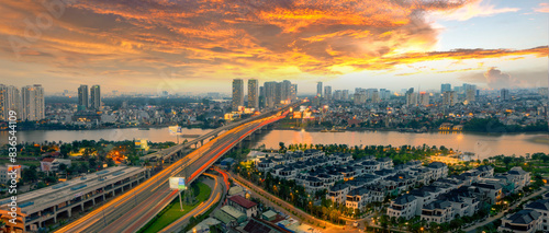 a panoramic view of Sai Gon bridge at sunset, showcasing the cityscape, vibrant skies, glowing traffic trails, and the dynamic growth of Ho Chi Minh City.