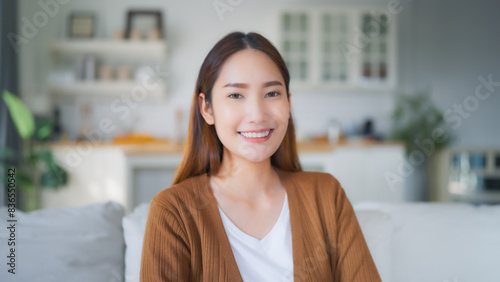 Portrait young asian woman smiling sitting on couch in living room and looking to camera, Facial expression happy