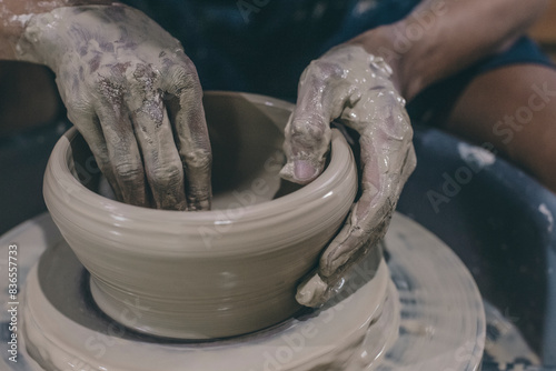 an artisan hand molding clay of pottery creating a ceramic bowl