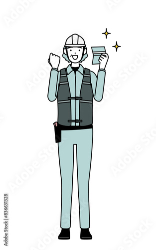Senior female engineer in helmet and work wear who is pleased to see a bankbook.
