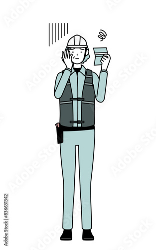 Senior female engineer in helmet and work wear looking at her bankbook and feeling depressed.