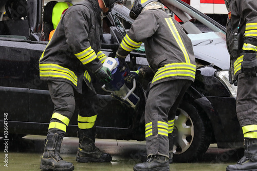 firefighter using cordless pneumatic shears to open the jammed door of a crashed car after a car accident